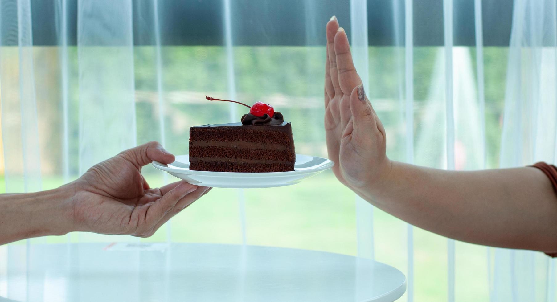 il donna rifiuta per mangiare il cioccolato torta su il mano. fermare mangiare dolci per perdere peso foto