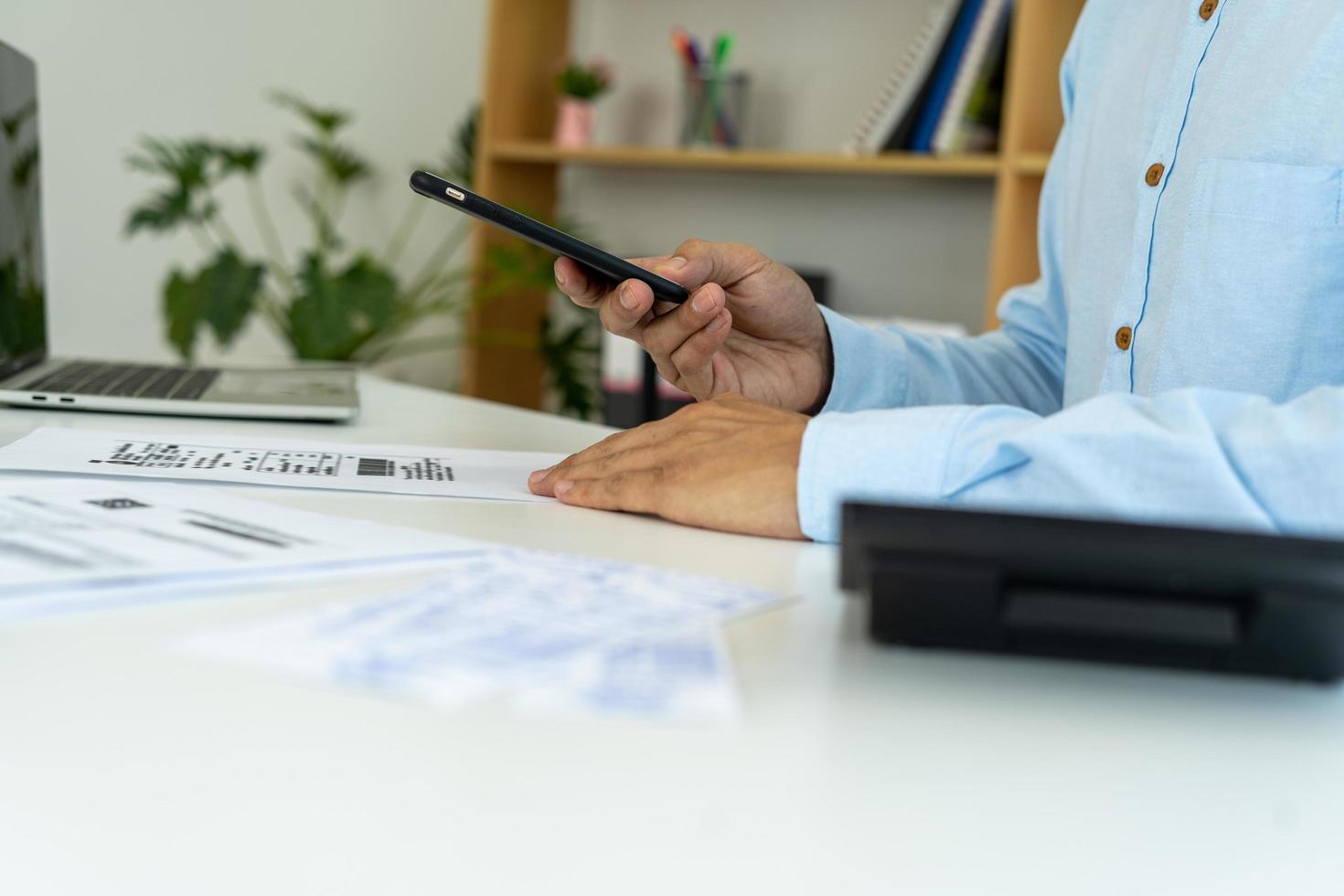 attività commerciale uomo uso Telefono per scansione codice a barre o qr codici per pagare credito carta conto dopo ricevente documento fattura in linea. pagami foto