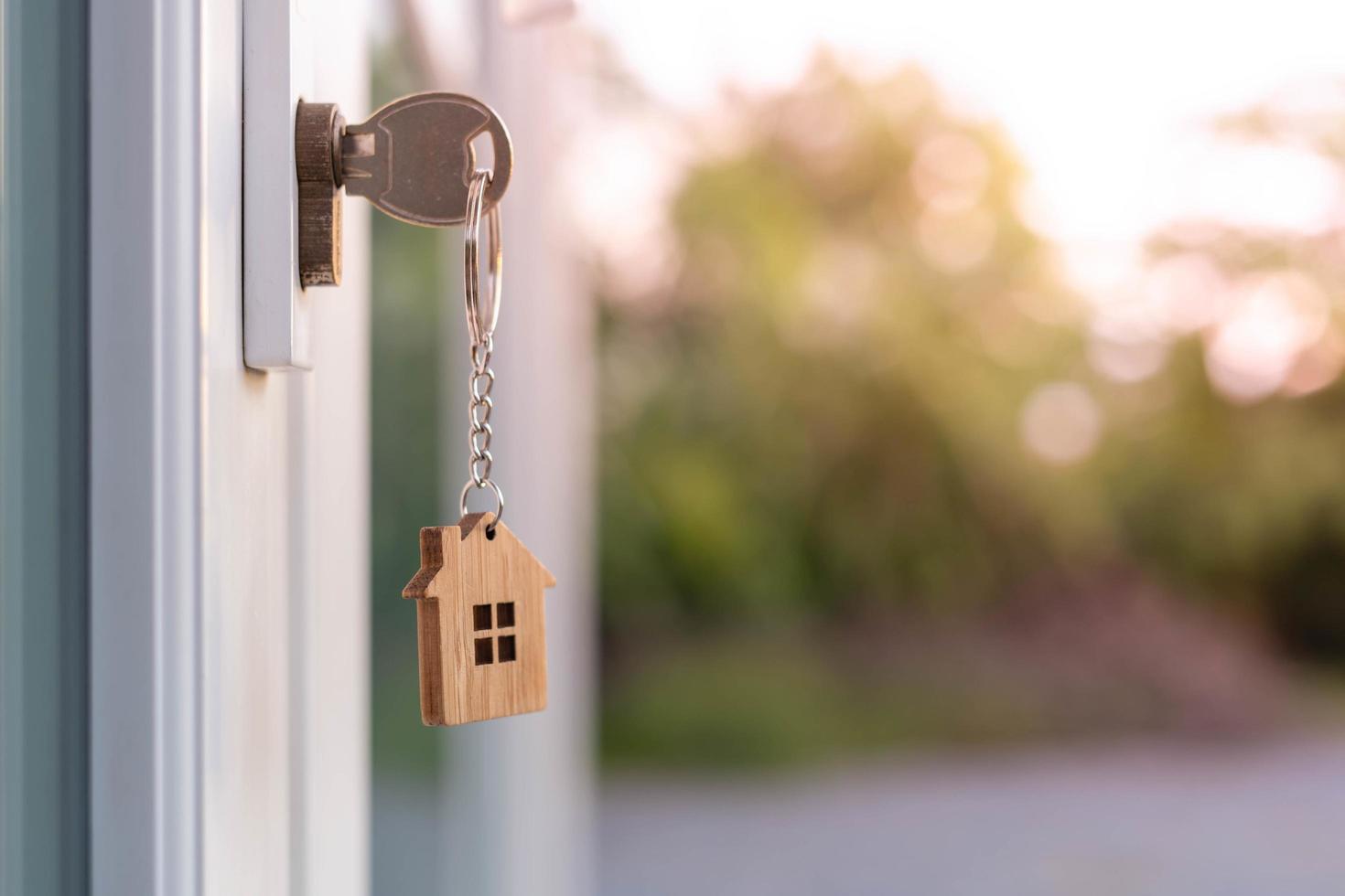 proprietario chiave per sblocco Casa è tappato in il porta. secondo mano Casa per affitto e saldi. portachiavi è soffiaggio nel il vento. mutuo per nuovo casa, acquistare, vendere, ristrutturare, investimento, proprietario, tenuta foto