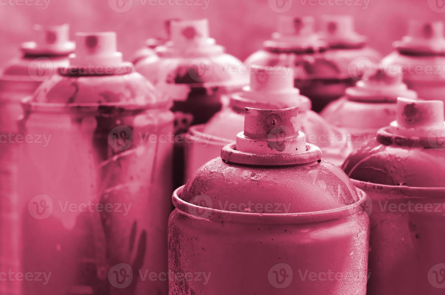 un' lotto di sporco e Usato aerosol lattine di dipingere. macro fotografia con superficiale profondità di campo. selettivo messa a fuoco su il spray ugello Immagine tonica nel Viva magenta, colore di il 2023 anno foto