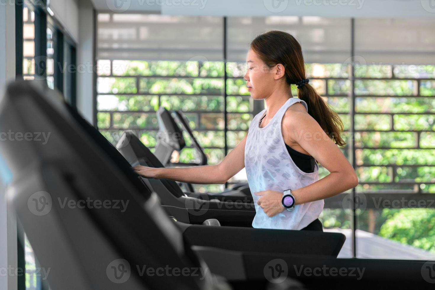 giovane contento asiatico donna atleta correre su tapis roulant, in esecuzione macchina, nel interno Palestra fitness per Salute foto