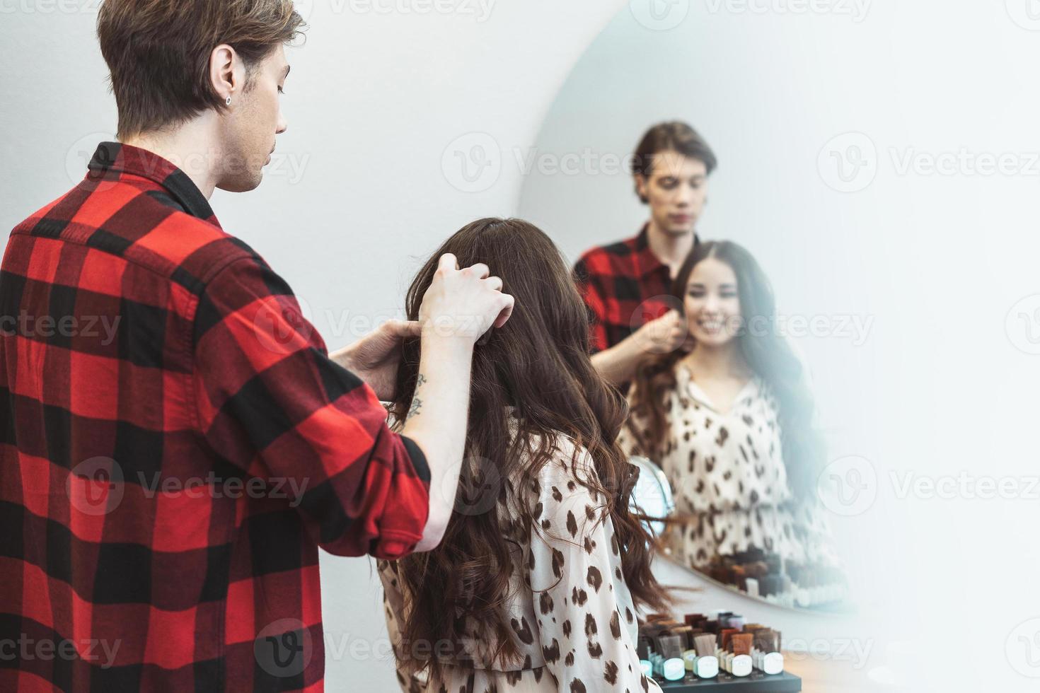 stilista barbiere messa in piega lungo capelli per bellissimo asiatico giovane donna nel il bellezza salone, Lavorando momento foto