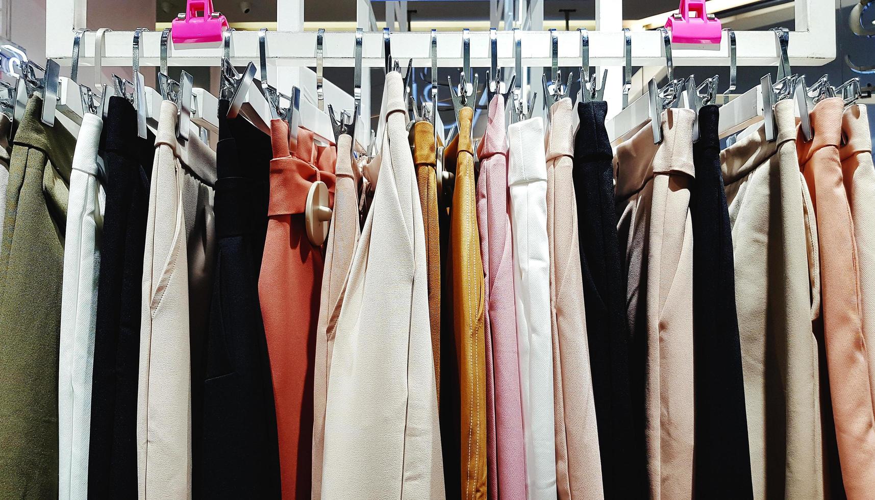 colorato di Da donna pantaloni sospeso su plastica grucce per vendita a moda memorizzare o donna Accessori negozio. cotone design. foto