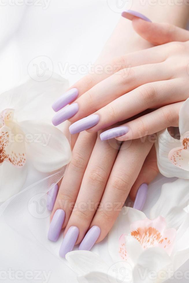 ragazze mani con delicato viola manicure e orchidea fiori foto