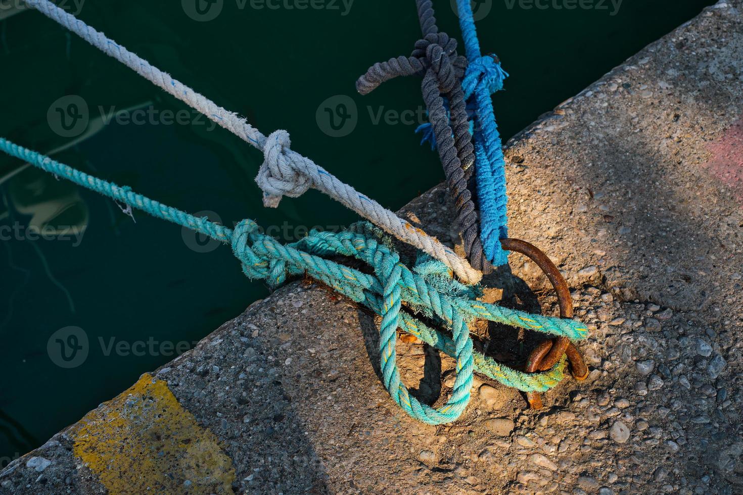 ormeggio squillare con legato blu e bianca nautico corda montato su un' calcestruzzo molo, marina sicurezza attrezzatura foto