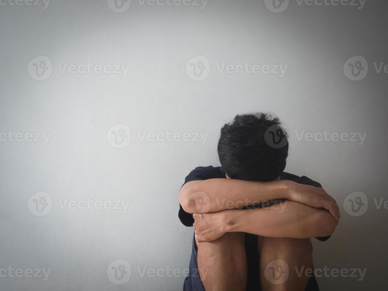 depresso uomo sedersi a il parete si sente senza speranza con vita foto