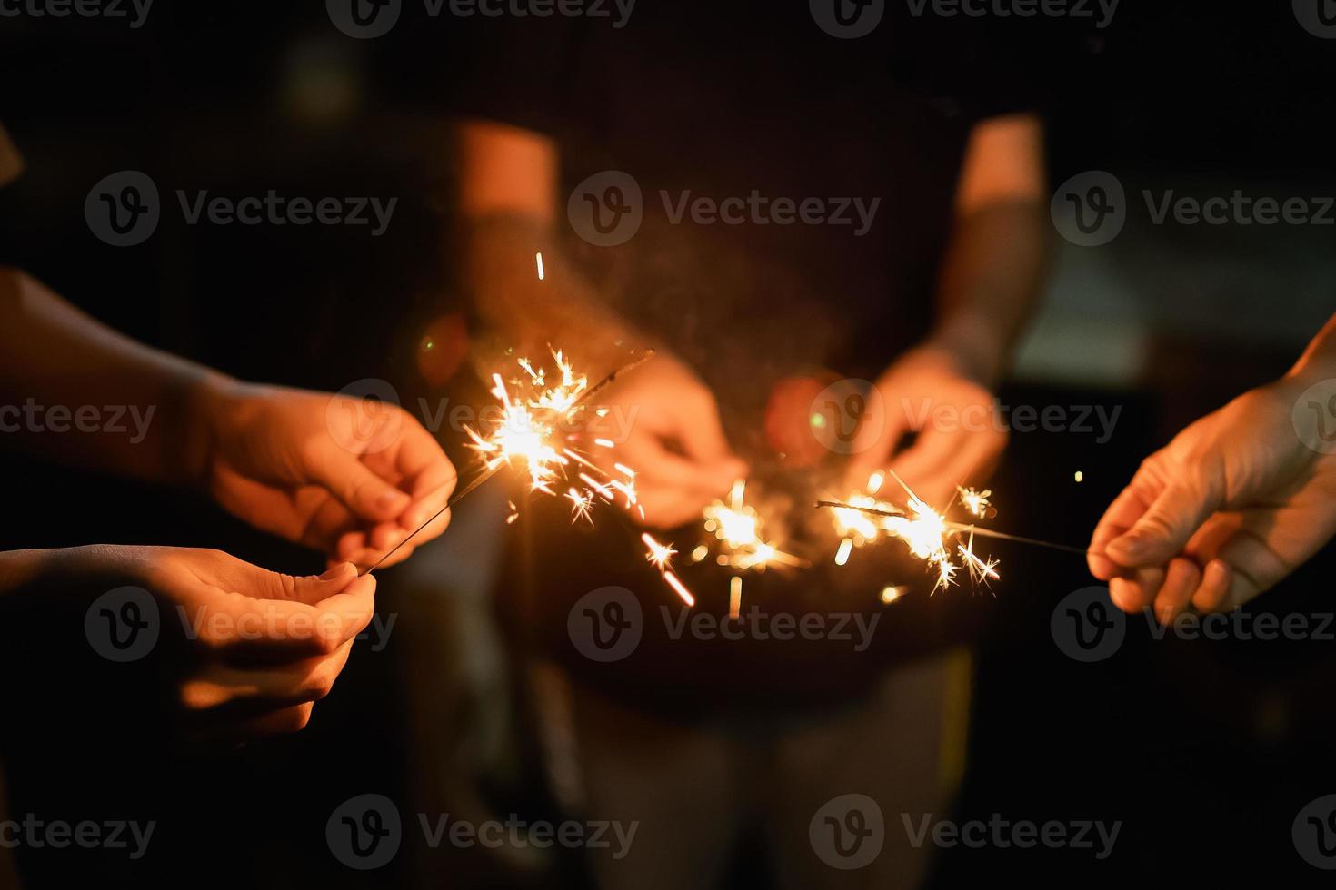 contento nuovo anno e allegro Natale gruppo di persone famiglia con sparkler fuoco illuminazione concetto, mano Tenere un' ardente sparkler fuoco d'artificio luce, avvicinamento donna mano con scintillare scuro. nuovo anno concetto. foto