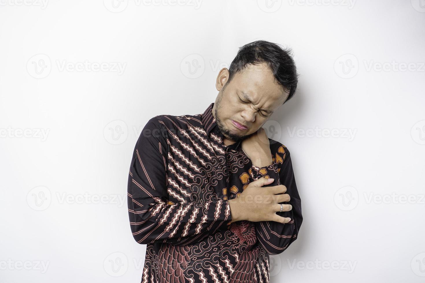 stanco irritato giovane uomo indossa batik camicia sofferenza a partire dal dolore, muscolo spasmo a posto di lavoro. fatica, Scadenza, dolore e scorretto posizione foto