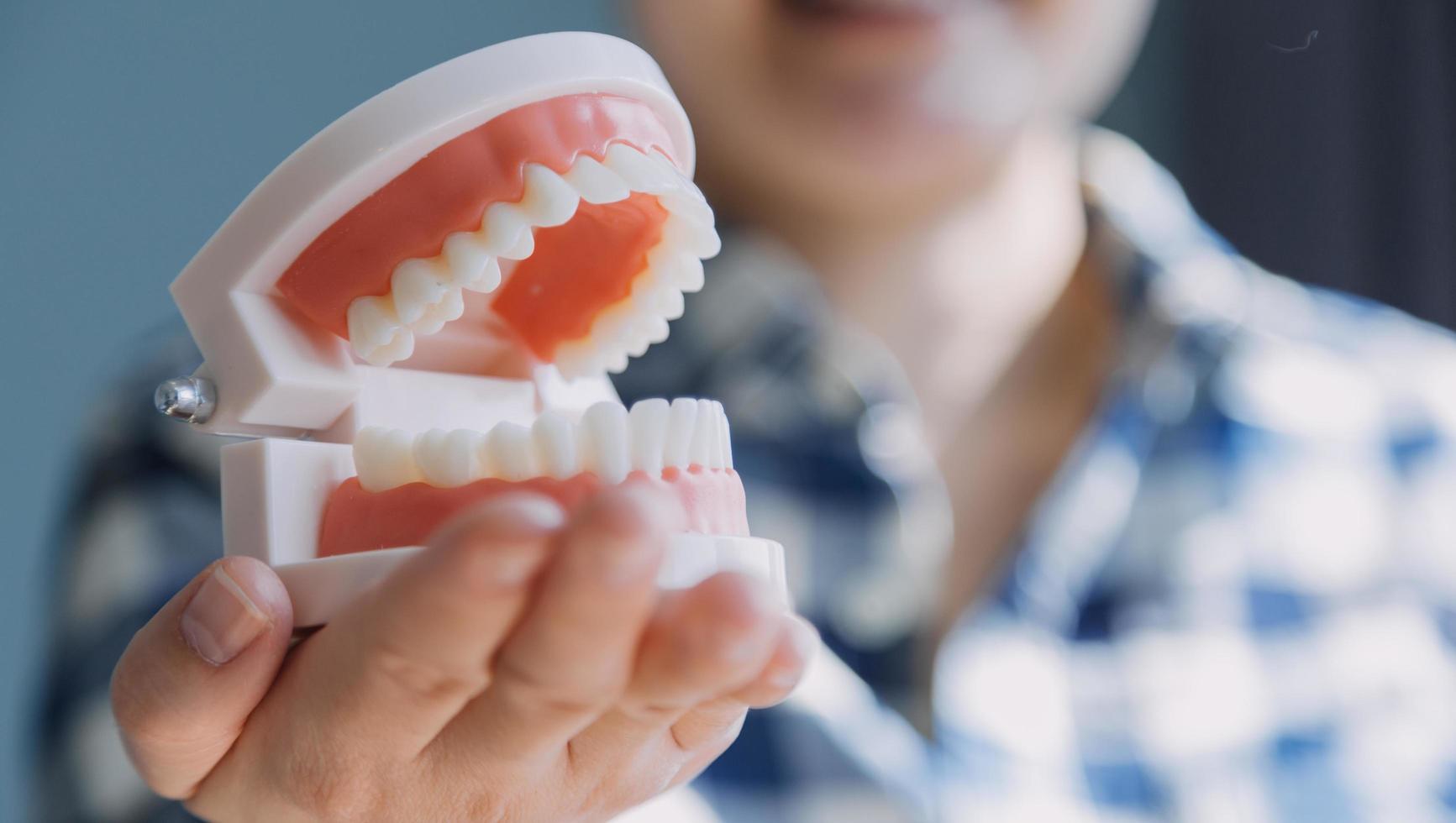 stomatologia concetto, parziale ritratto di ragazza con forte bianca denti guardare a telecamera e sorridente, dita vicino viso. avvicinamento di giovane donna a dal dentista, studio, in casa foto