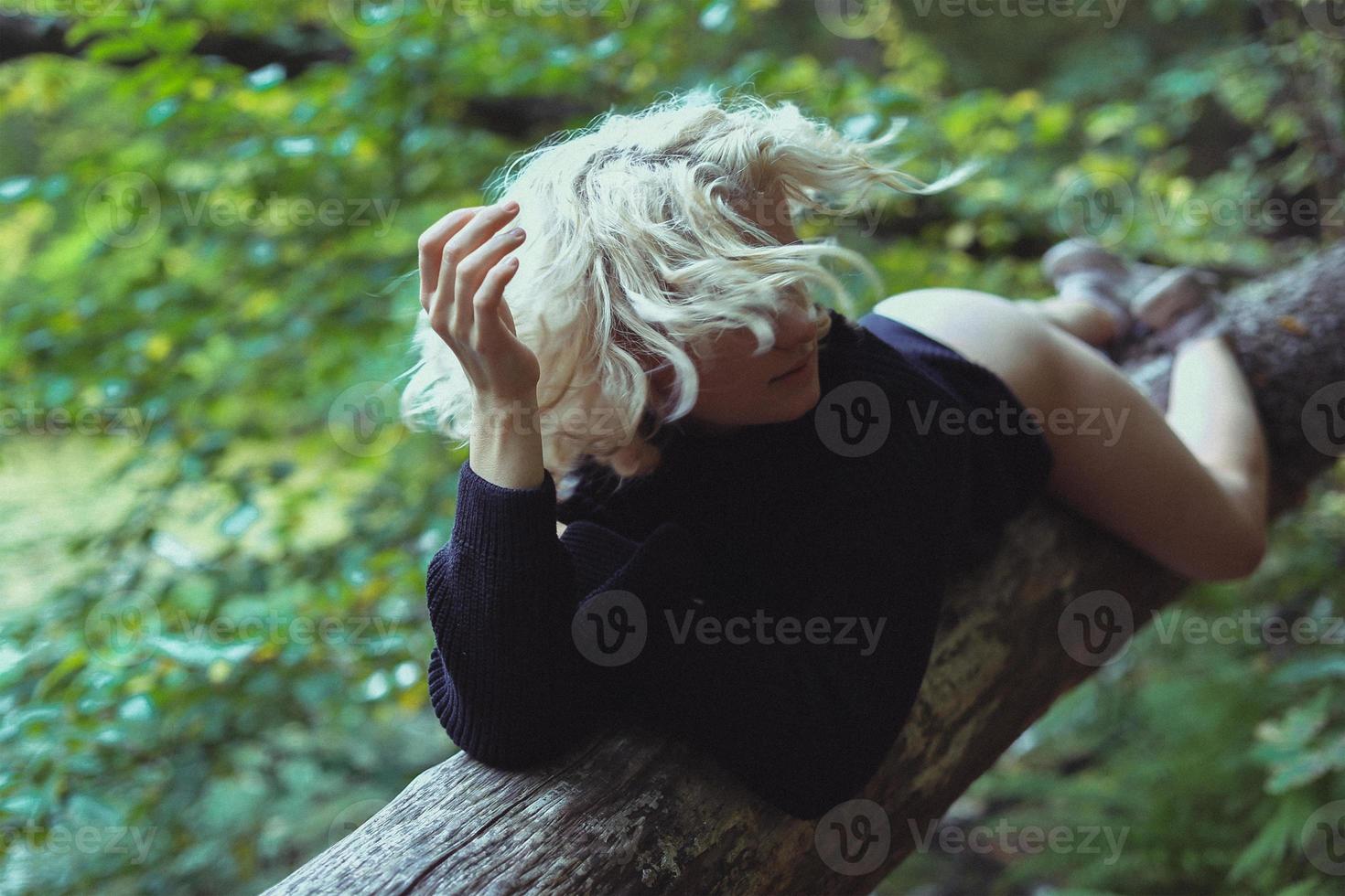 giovane donna con spoglio indietro su albero tronco nel legna panoramico fotografia foto