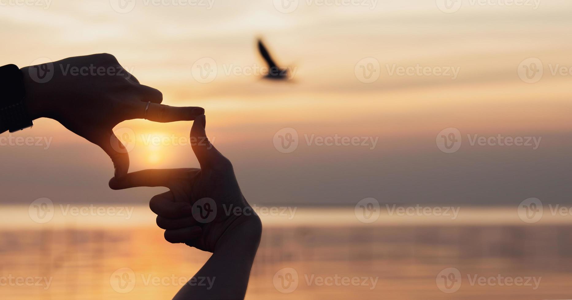 pianificazione e visione concetto di nuovo anni inizio, donna mani fabbricazione telaio gesto trova messa a fuoco a tramonto, donna guardare per prospettiva per catturare il senso di un' chiaro imminente obbiettivo. foto