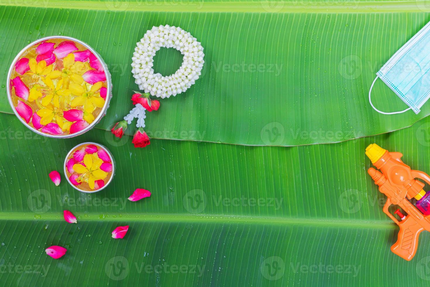 sfondo del festival songkran con fiori di ghirlanda di gelsomino in una ciotola di acqua, profumo e calcare su uno sfondo verde foglia di banana bagnata. foto