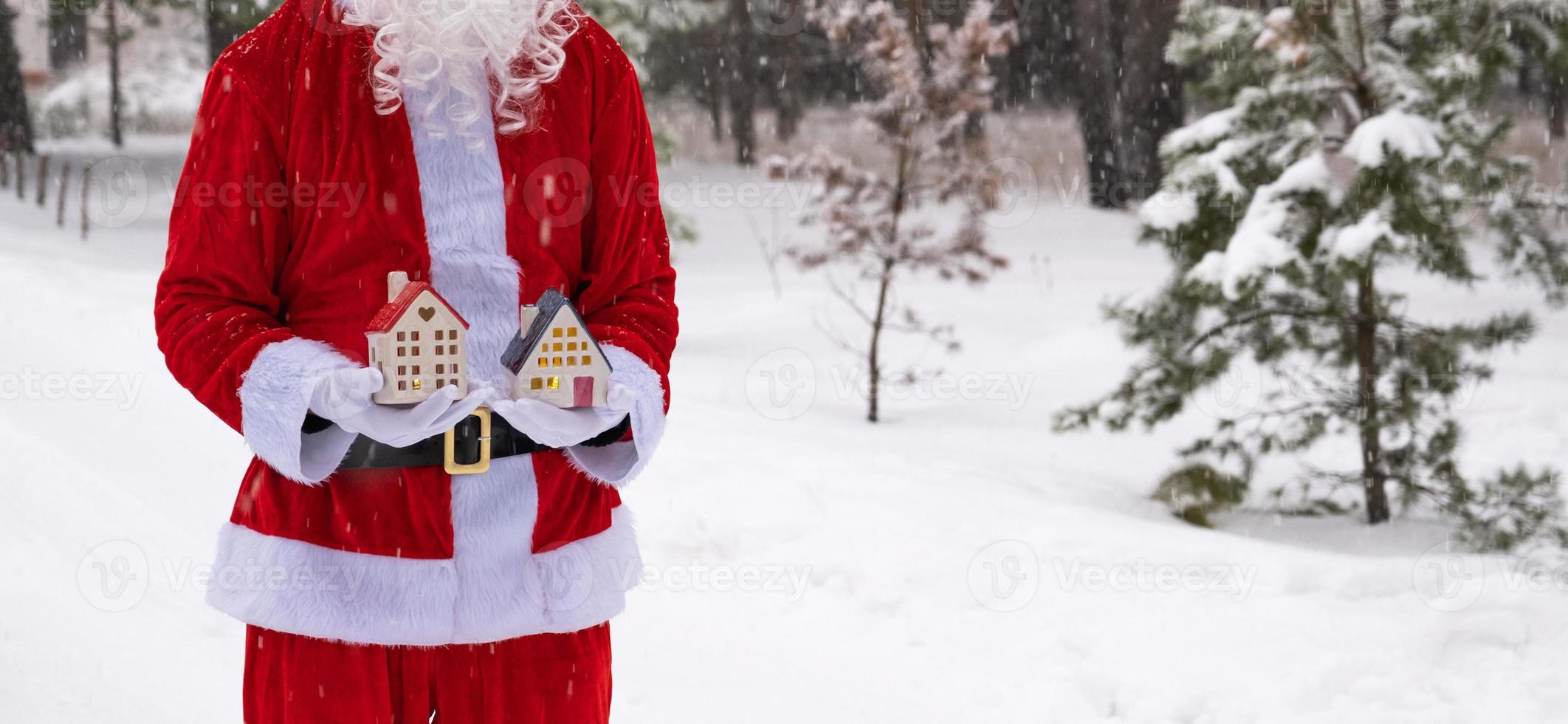 chiave di casa con portachiavi cottage nelle mani di babbo natale all'aperto nella neve. affare per immobili, acquisto, costruzione, trasloco, mutuo. casa accogliente. buon natale, evento di prenotazione di capodanno e sala foto