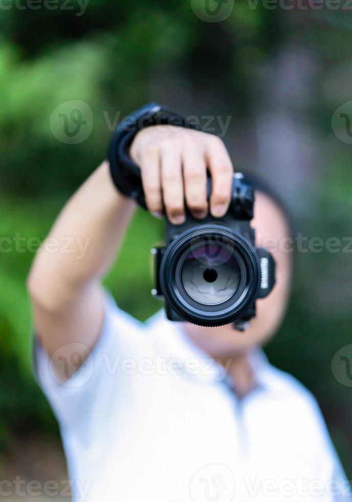 asiatico uomo detiene il medio formato telecamera nel il suo mano e messa a fuoco per sparare nel davanti di lui. foto