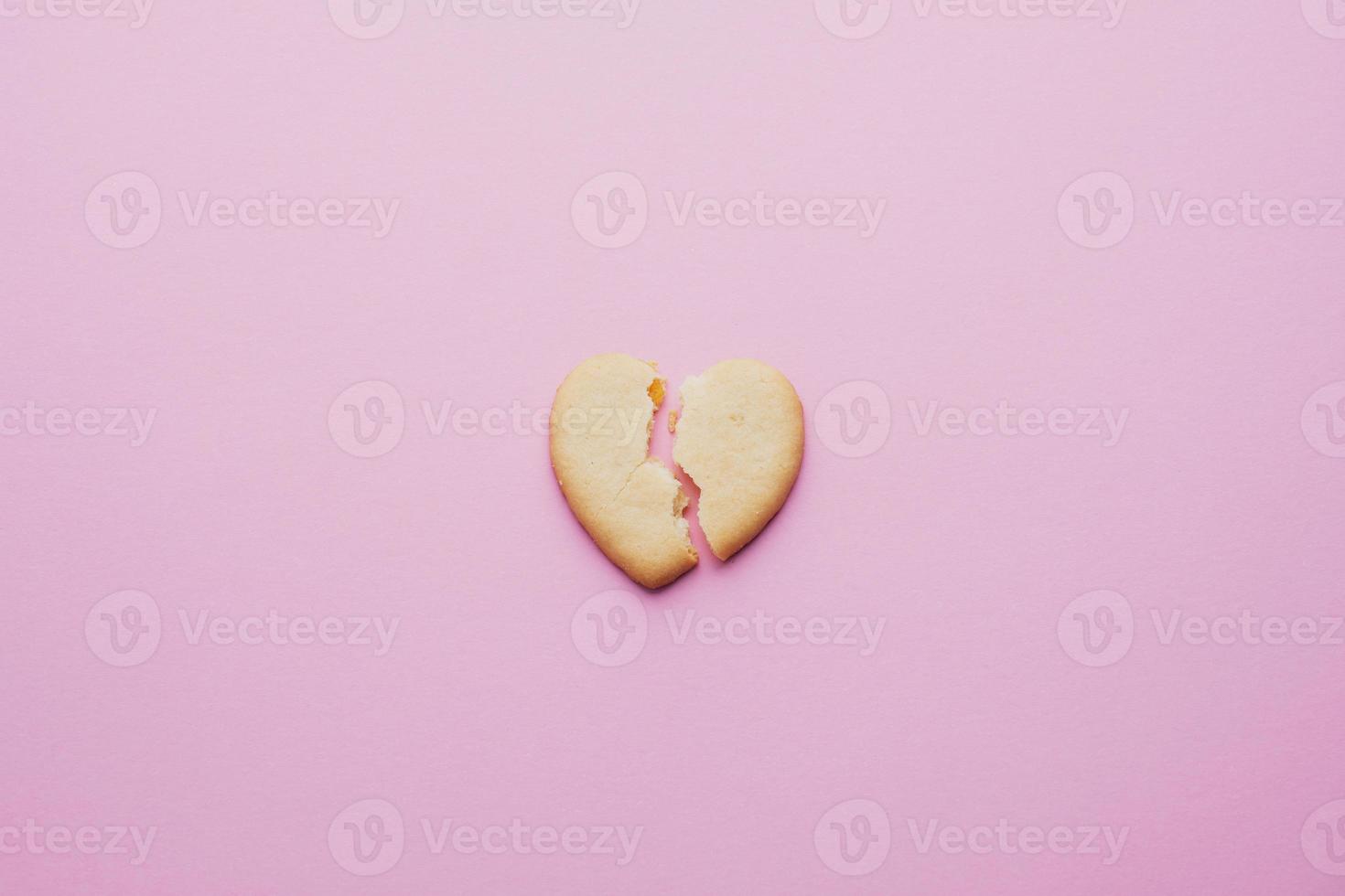 cuore sagomato biscotti, un' Cracked cuore su un' rosa sfondo, il concetto di un' rotto relazione. foto