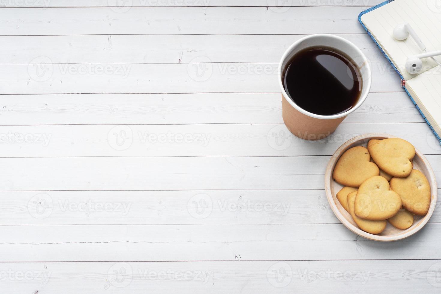 nero caffè nel un' carta tazza e biscotti nel il forma di cuori su un' bianca sfondo. piatto posare copia spazio, superiore Visualizza. foto