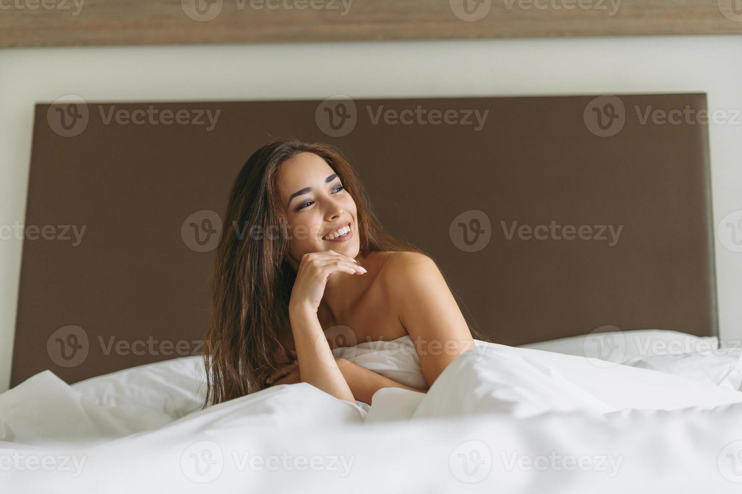 bellissimo giovane asiatico donna con lungo capelli nel letto con bianca lenzuola di il Hotel camera foto