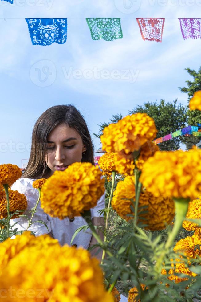 giovane carino donna odorare arancia fiori, nel un' campo di cempasuchil fiori Messico foto