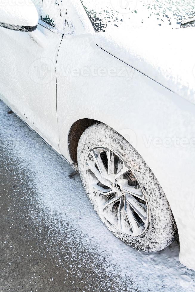 mano lavaggio con alto pressione acqua nel un' auto lavare fuori. il auto è pieno di schiuma. il concetto di mano lavaggio, self service. foto