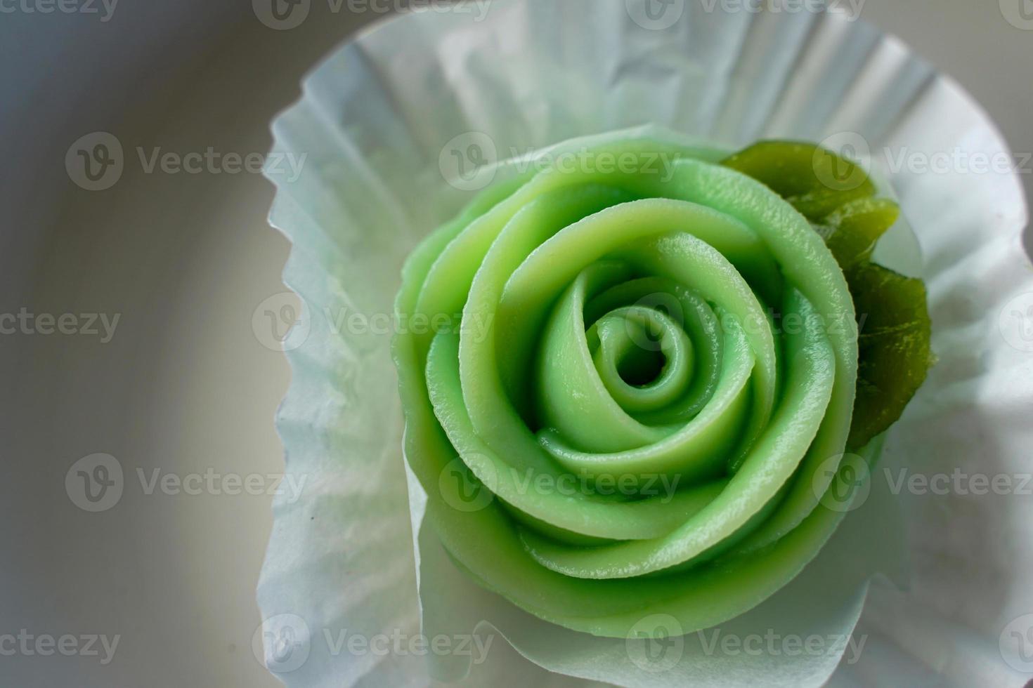 ar lua, tradizionale tailandese dolci scolpito nel il forma di un' verde rosa a partire dal pandan le foglie. servito su un' bianca ceramica piatto. morbido e selettivo messa a fuoco. foto