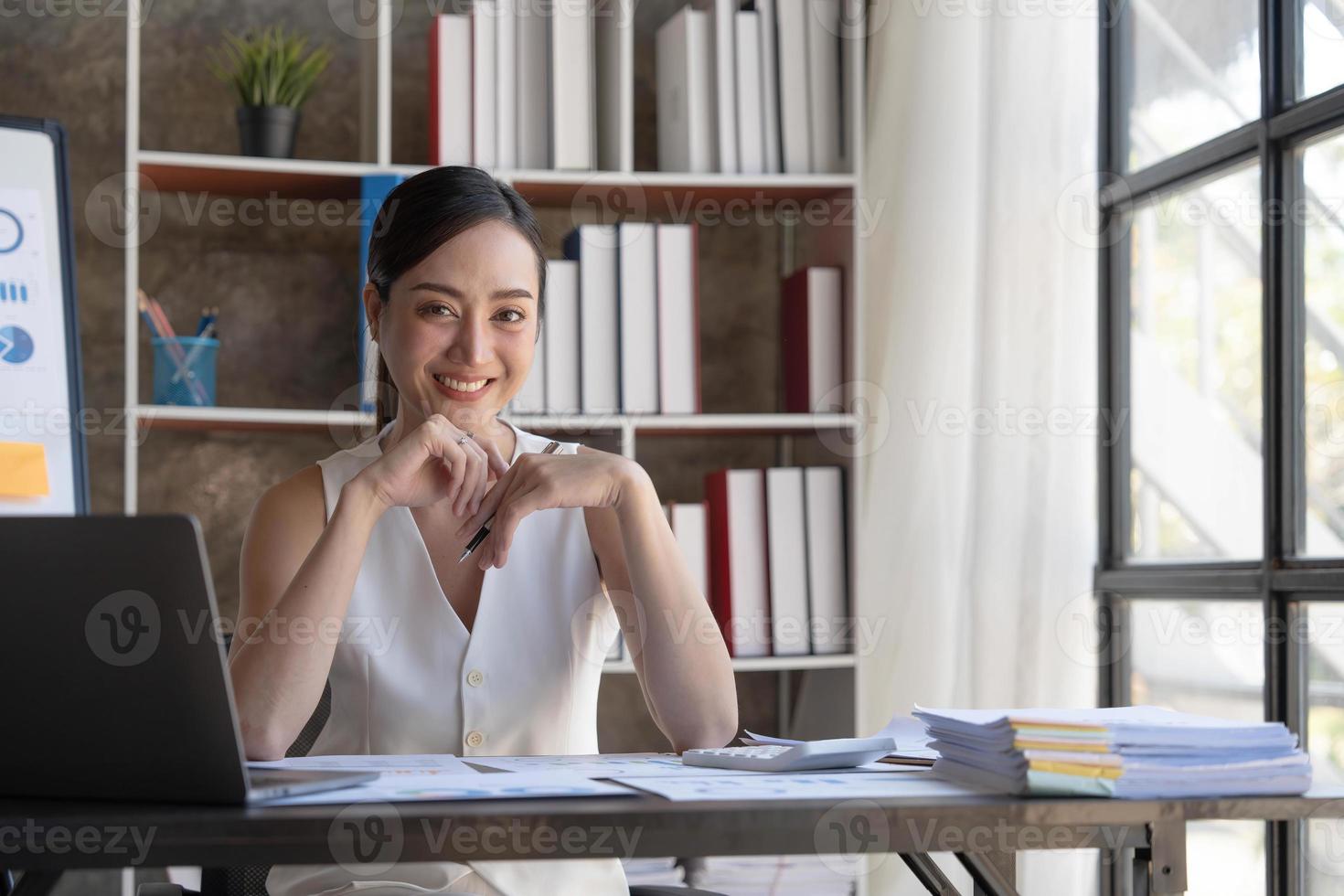 bellissimo giovane sorridente asiatico donna d'affari Lavorando su il computer portatile. Asia donna d'affari Lavorando documento finanza e calcolatrice nel sua ufficio. foto