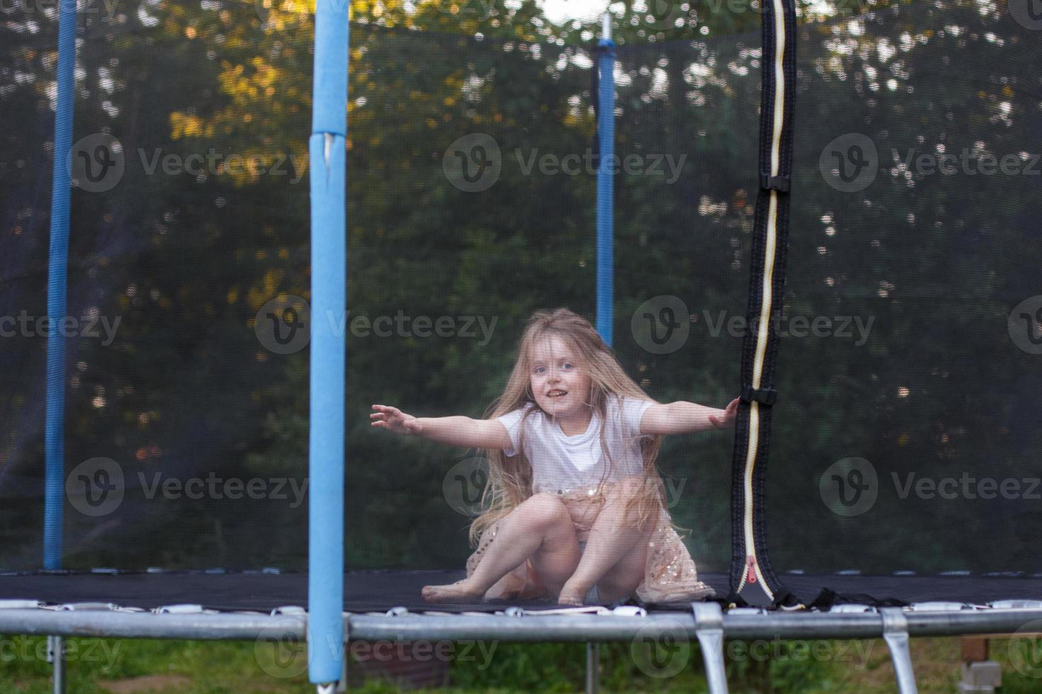 poco bambino ragazza salto su il trampolino nel il indietro cortile foto