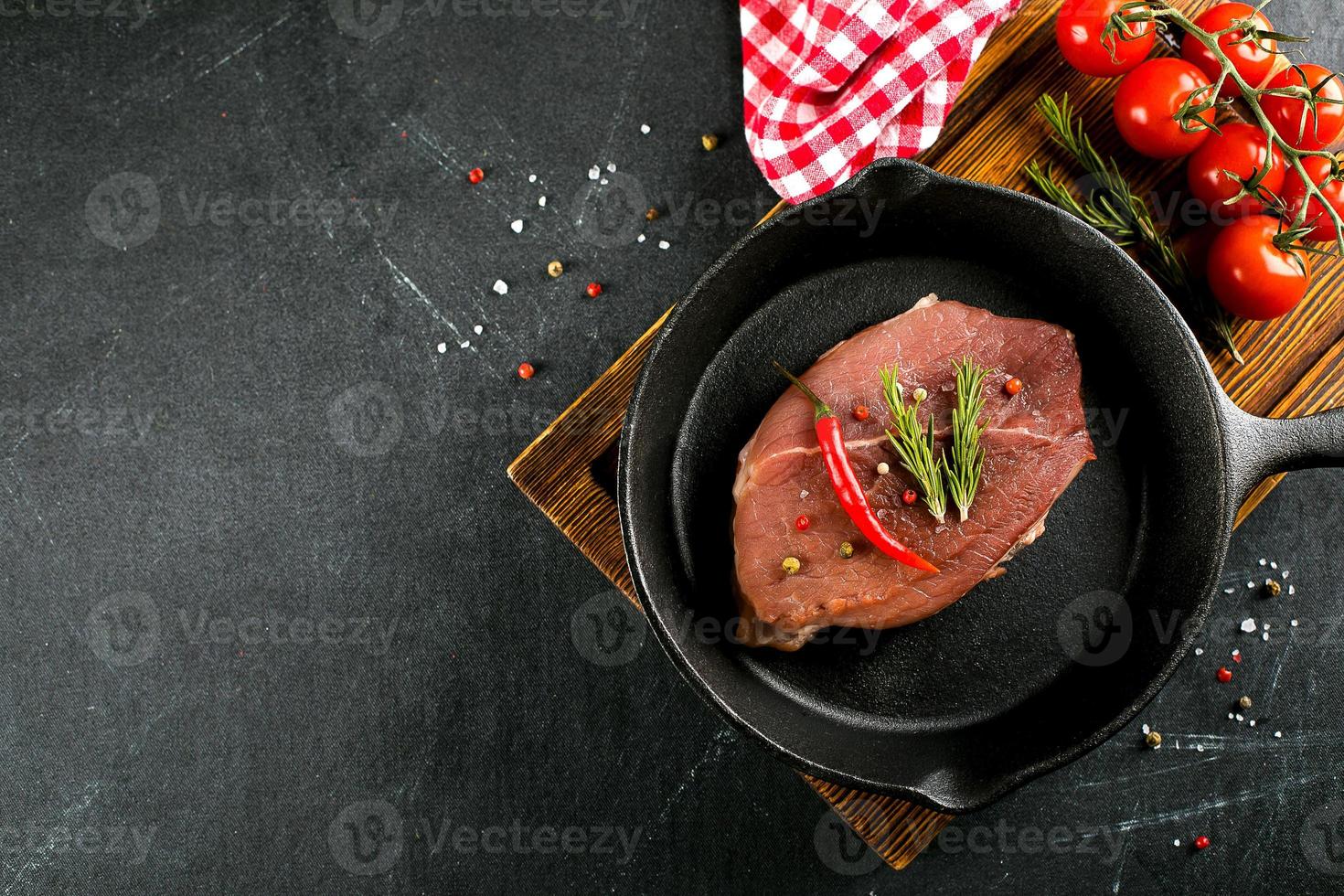 crudo carne nel nero ghisa padella. Maiale bistecche con spezie, erbe aromatiche buio sfondo. superiore Visualizza foto