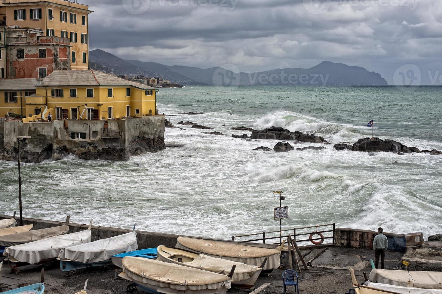 mare nel tempesta su rocce di italiano villaggio foto