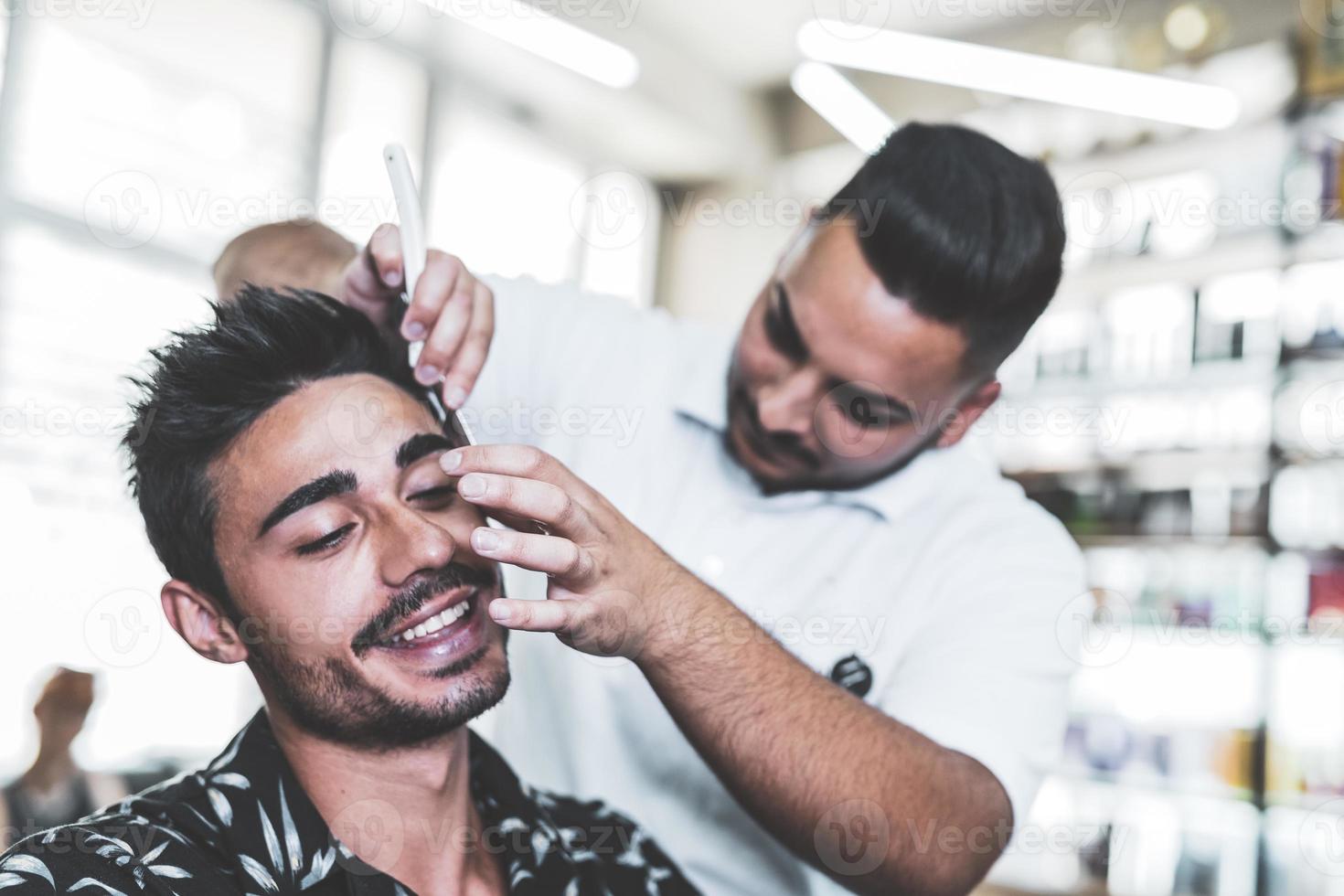 bello arabo uomo è ottenere rasato di parrucchiere a il barbiere foto