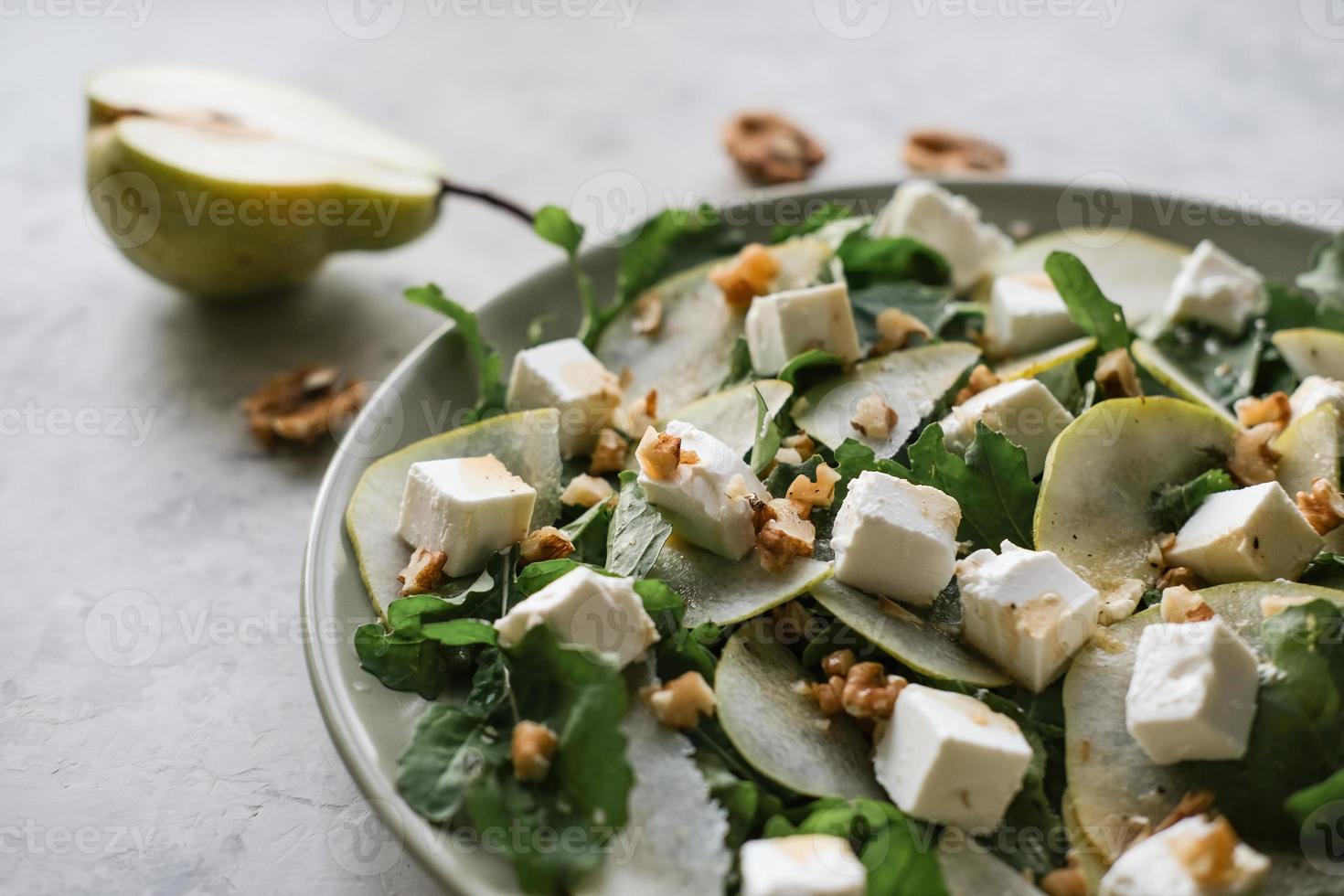 insalata con rucola, Pera, feta formaggio e Noci. delicatezza insalata su un' piatto su un' grigio sfondo foto