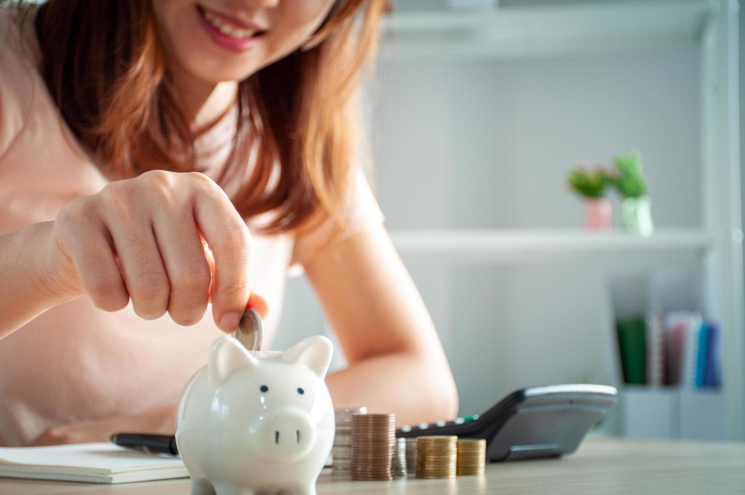 contento asiatico donne mettere i soldi nel un' porcellino banca. Salva i soldi concetto foto