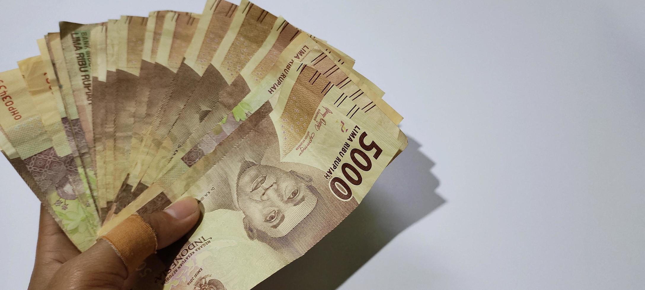 parecchi lenzuola di 5000 indonesiano rupia banconote nel mano isolato su bianca sfondo. i soldi concetto sfondo foto