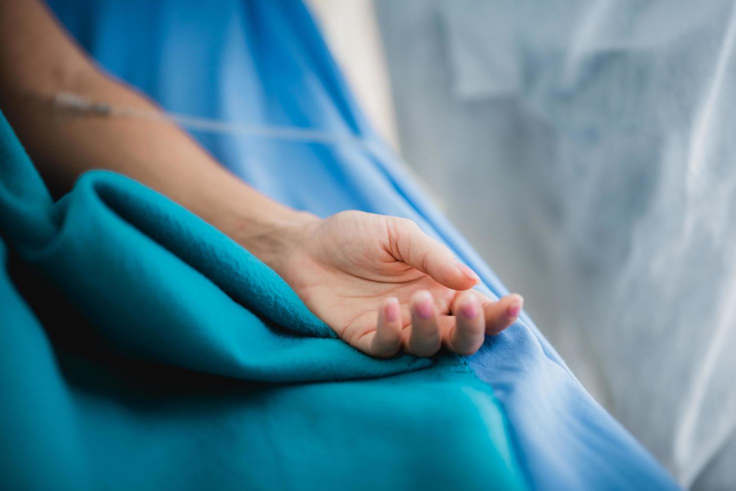 primo piano la mano di un paziente in un letto d'ospedale foto