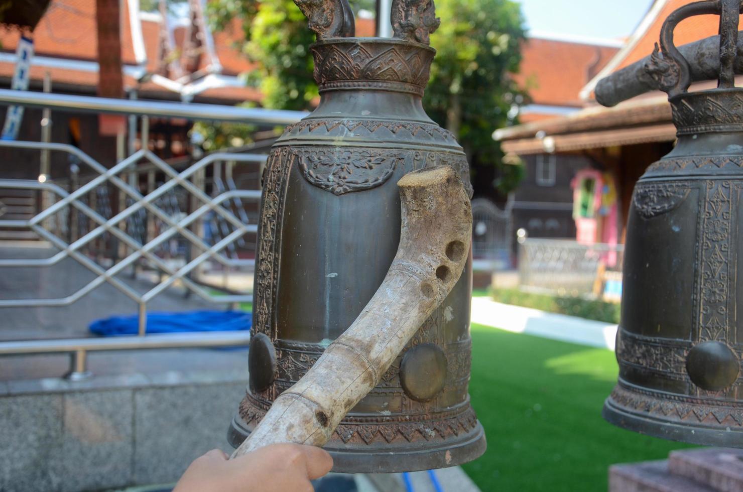 donna mano Tenere un' di legno martello per campana carillon nel un' buddista tempio foto