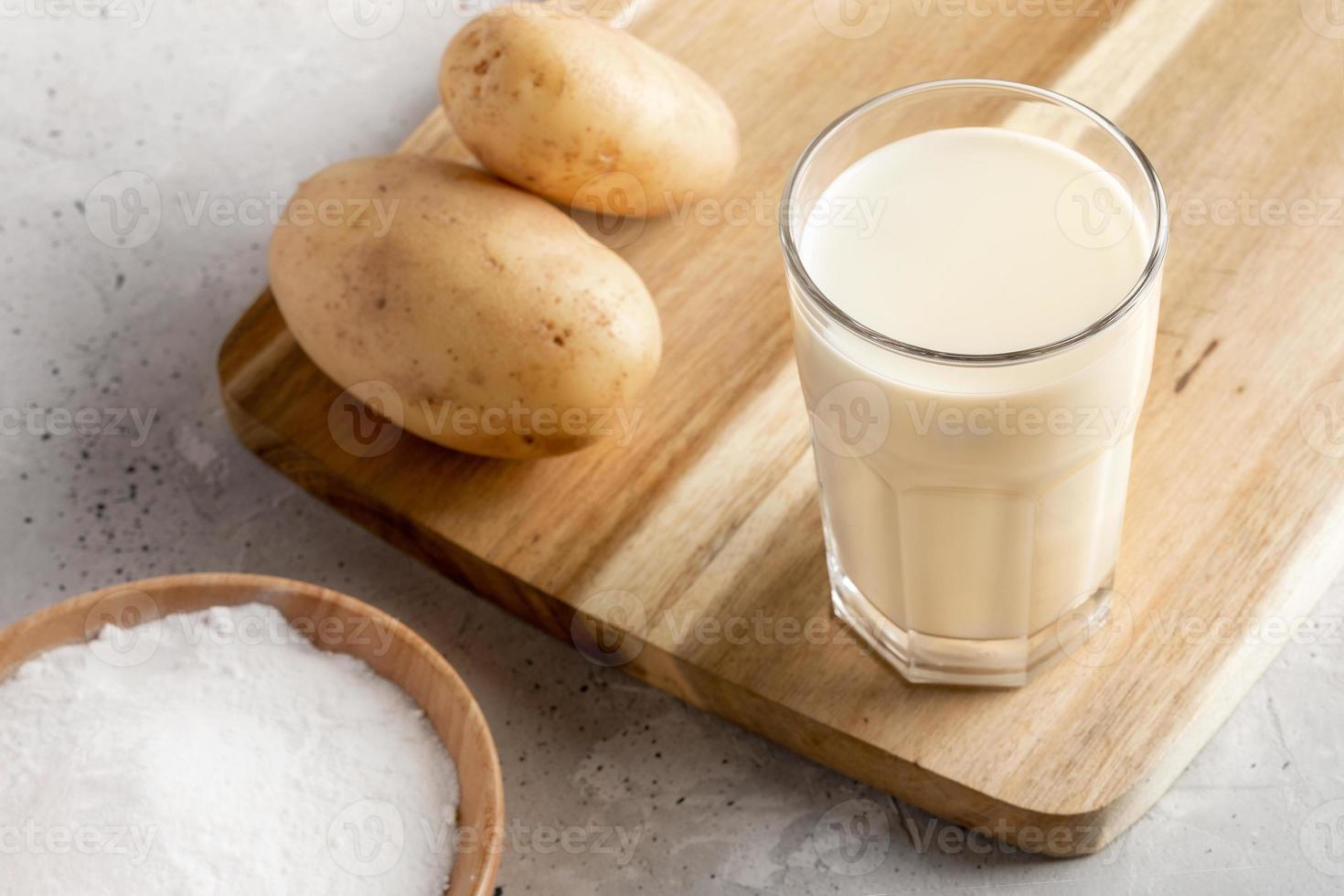 in polvere vegano Patata latte bicchiere, Patata polvere e tuberi su calcestruzzo sfondo. vicino su. foto