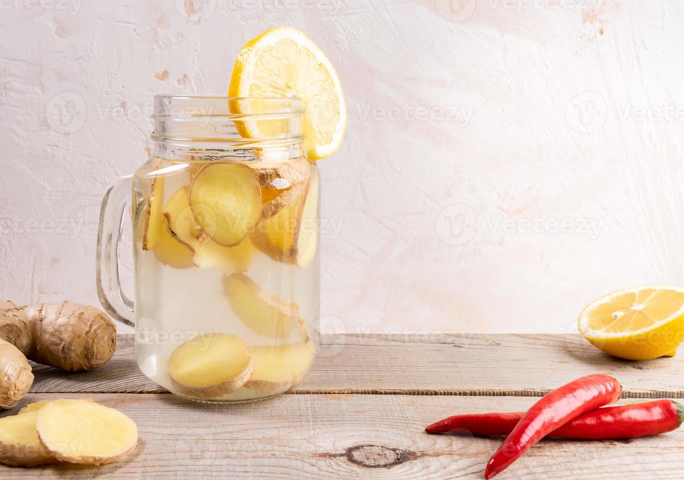 bicchiere vaso pieno con Zenzero acqua e spies su di legno tavolo su leggero sfondo. foto