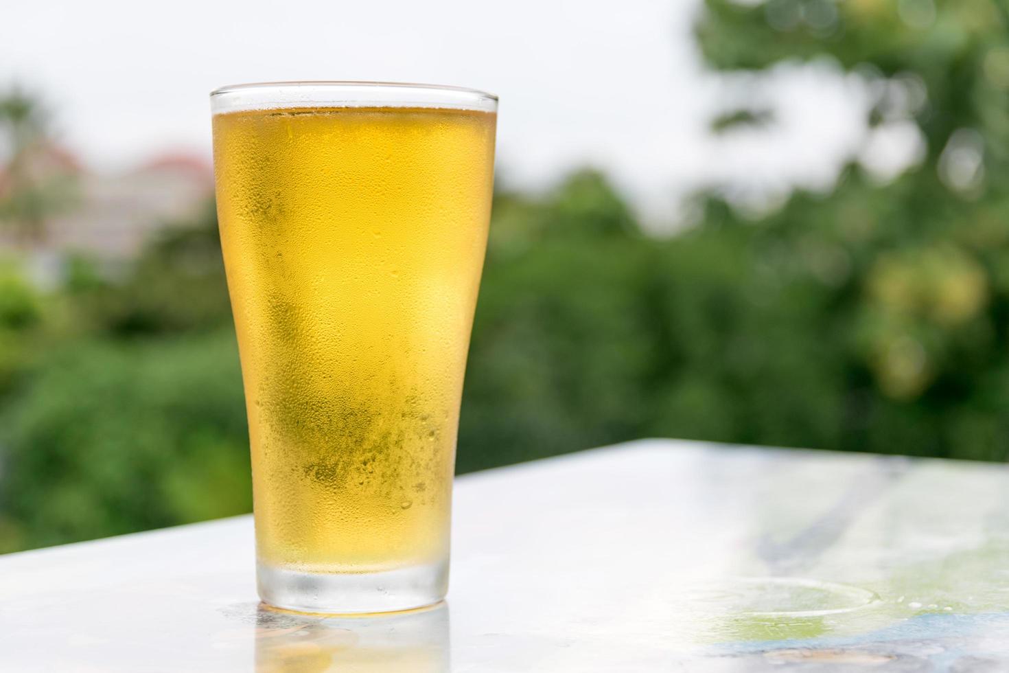 una pinta di birra su sfondo naturale linea degli alberi foto