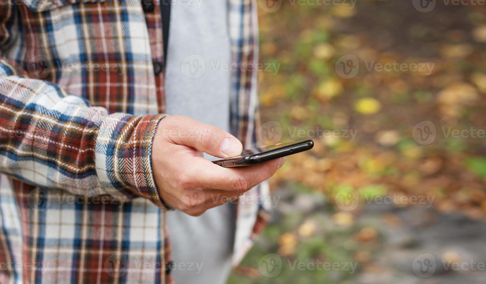 un' uomo su un' città strada sembra in il suo smartphone. il mondo di mobile comunicazioni e il Internet. foto