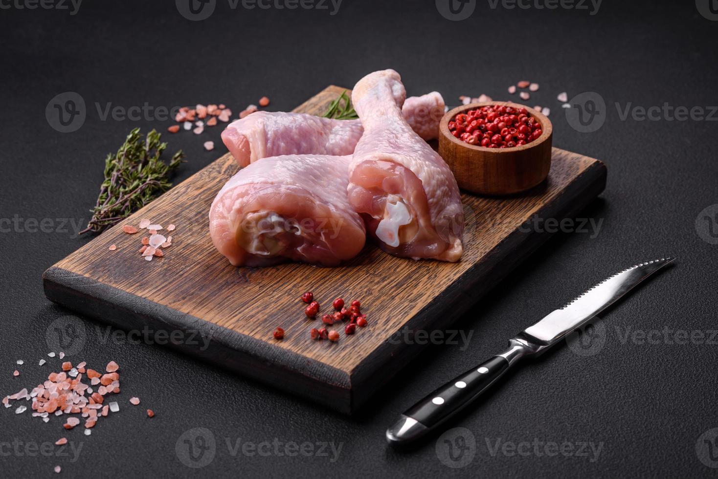 tre crudo pollo gambe con spezie e erbe aromatiche su un' di legno taglio tavola foto