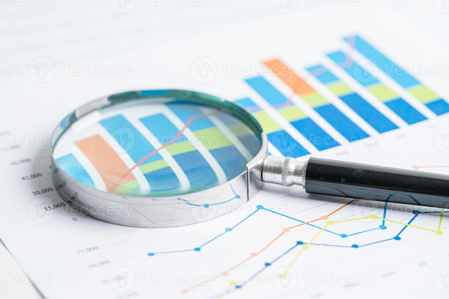 lente di ingrandimento su carta millimetrata grafici. sviluppo finanziario, conto bancario, statistiche, economia dei dati di ricerca analitica degli investimenti, negoziazione di borsa, concetto di ufficio commerciale. foto