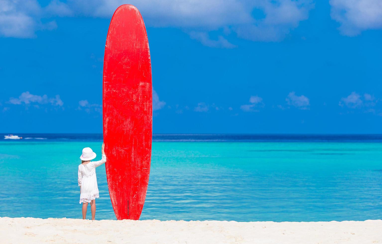 ragazza in piedi con una tavola da surf rossa foto