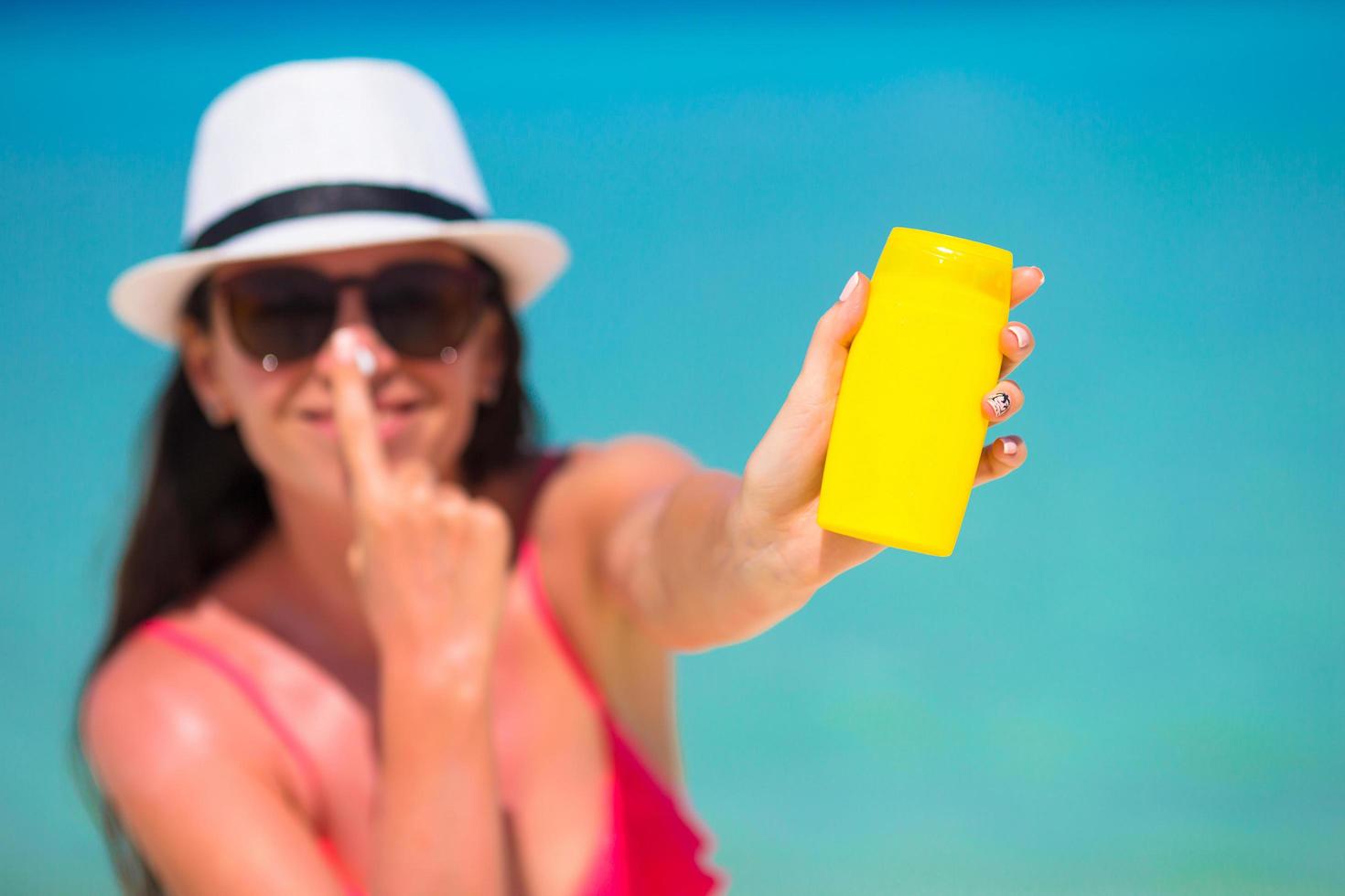 donna che tiene una bottiglia di crema solare foto