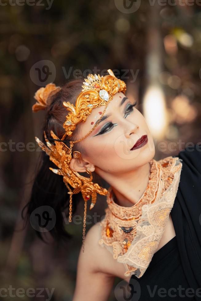 avvicinamento viso di un asiatico donna nel trucco indossare oro corona e oro Accessori con bellissimo facce foto