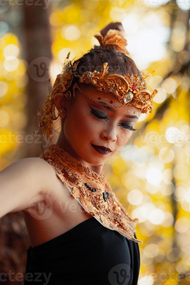 ritratto di asiatico donna indossare un' oro corona e oro collana con sua bellissima trucco nel nero vestito foto