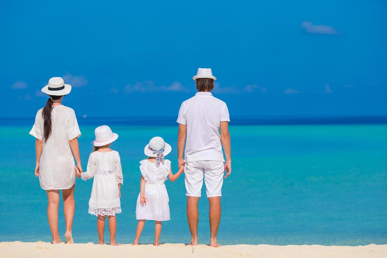 famiglia in piedi su una spiaggia in abiti bianchi foto