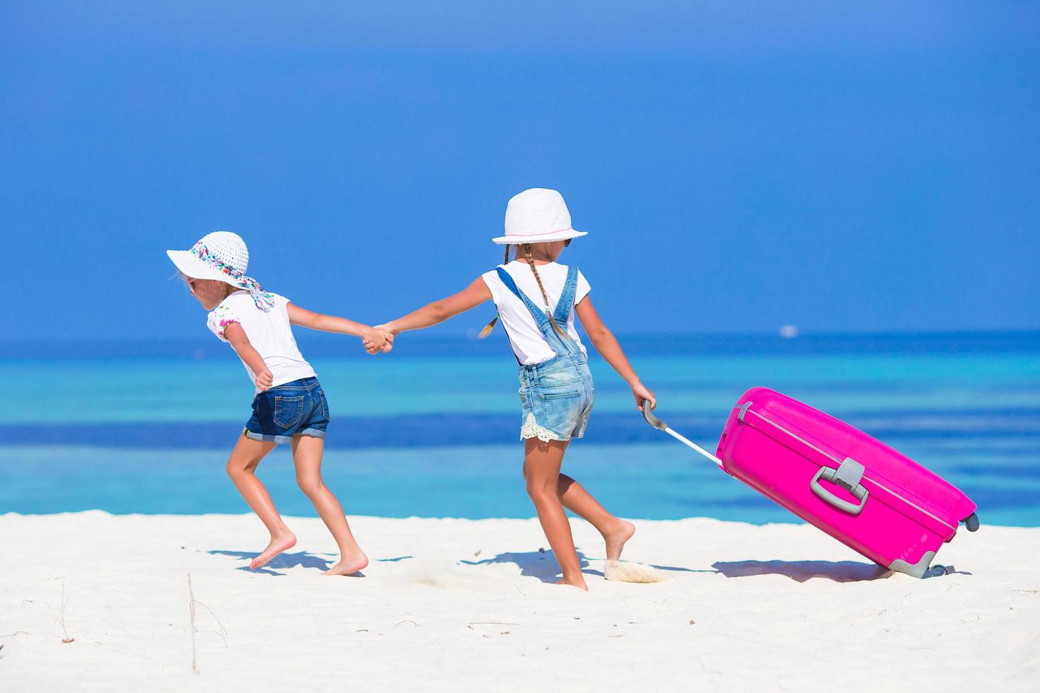 due ragazze che corrono con i bagagli su una spiaggia foto