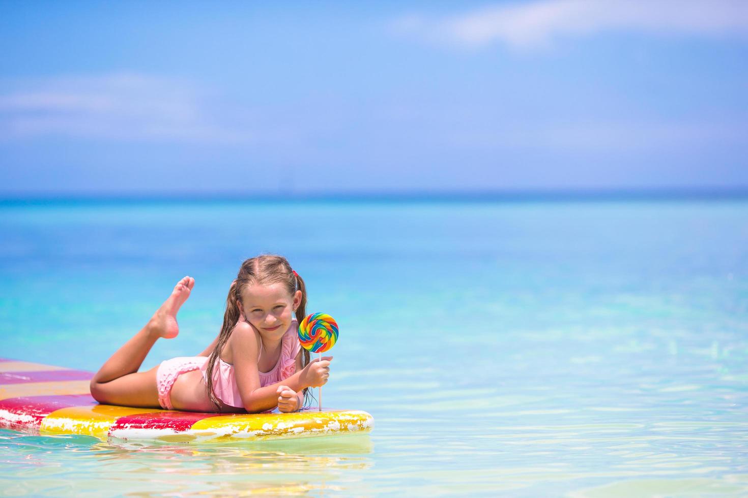 ragazza con lecca-lecca su una tavola da surf foto