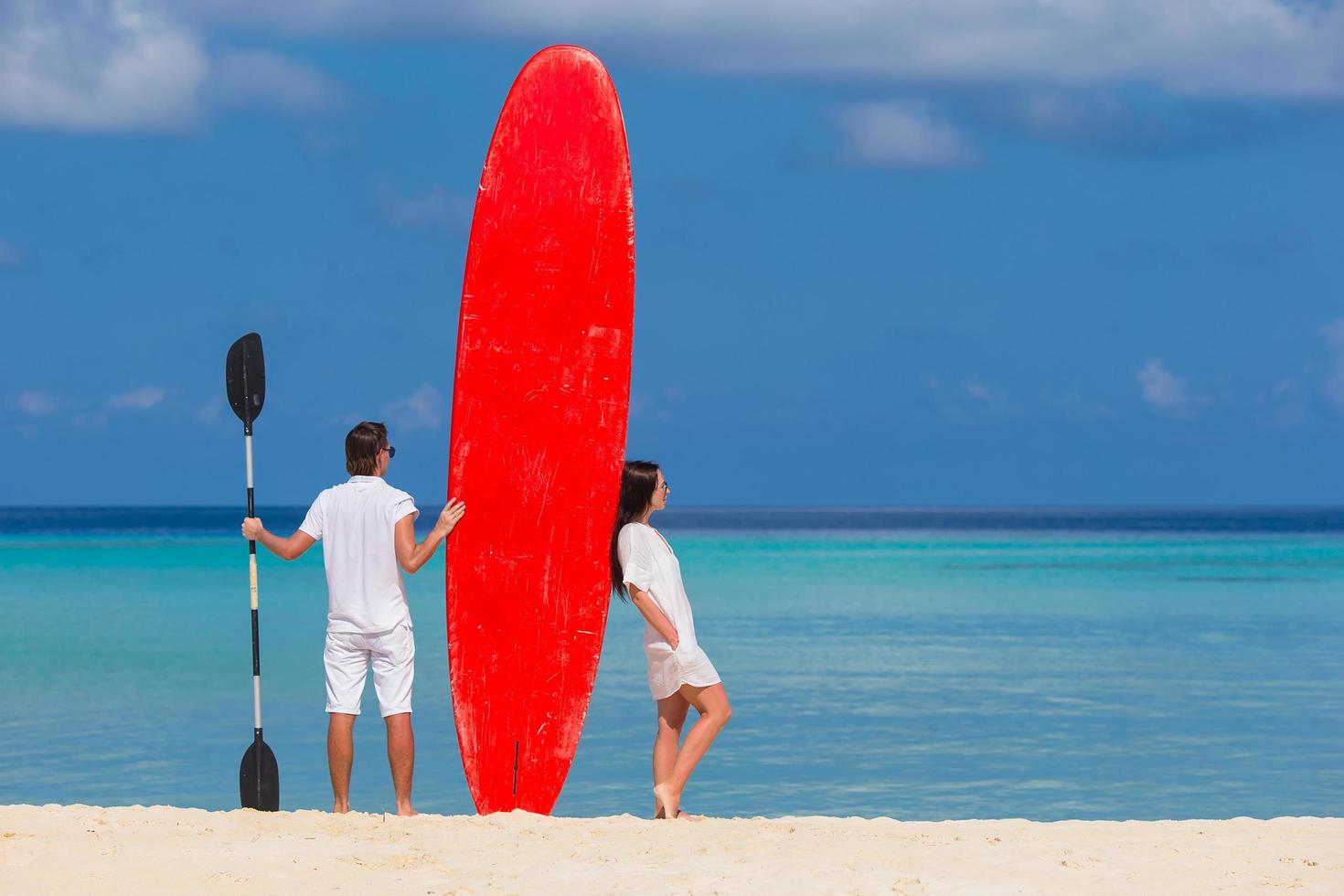 coppia con un paddleboard in spiaggia foto