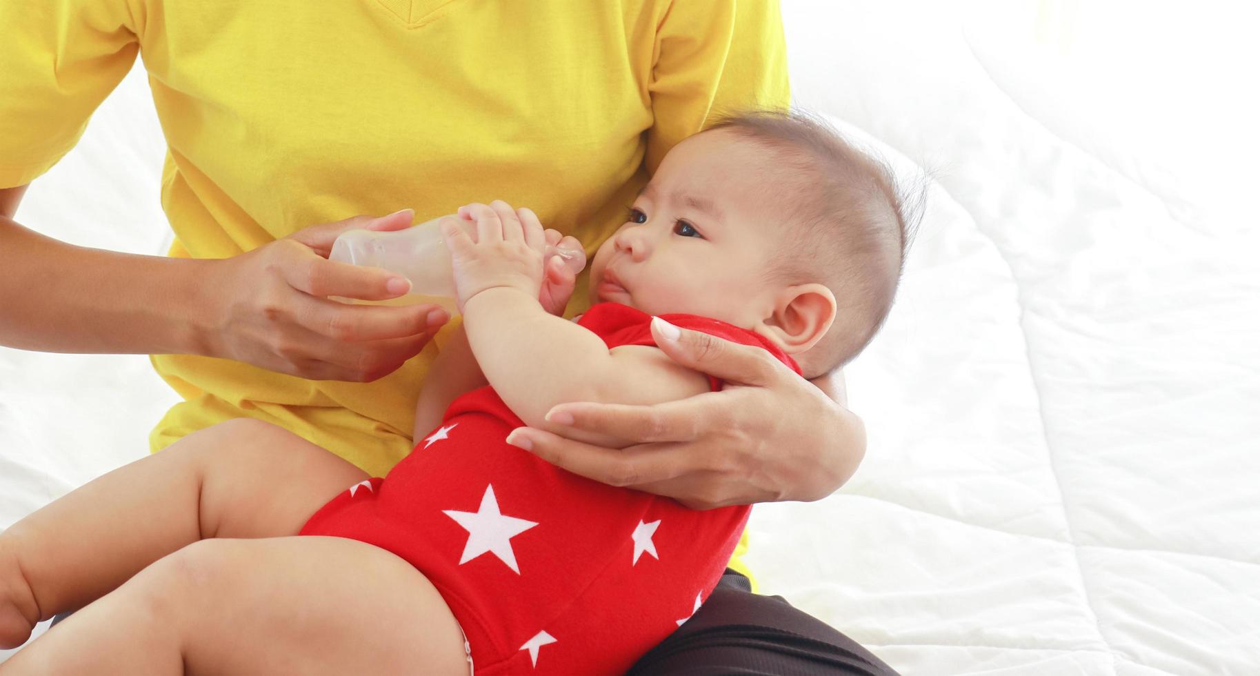 madre che allatta un bambino con una bottiglia foto