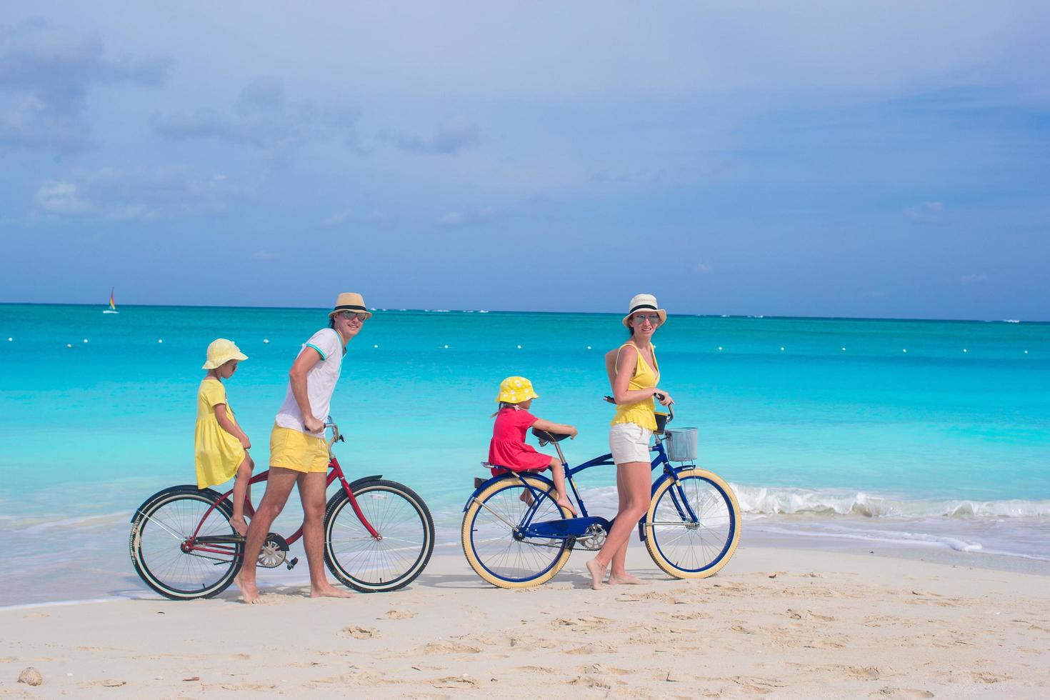 famiglia in sella a biciclette su una spiaggia bianca foto